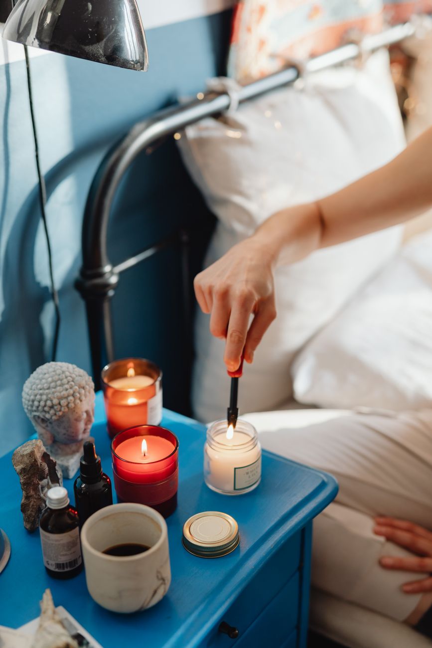 A person lights candles on a bedside table creating a cozy and relaxing atmosphere.
